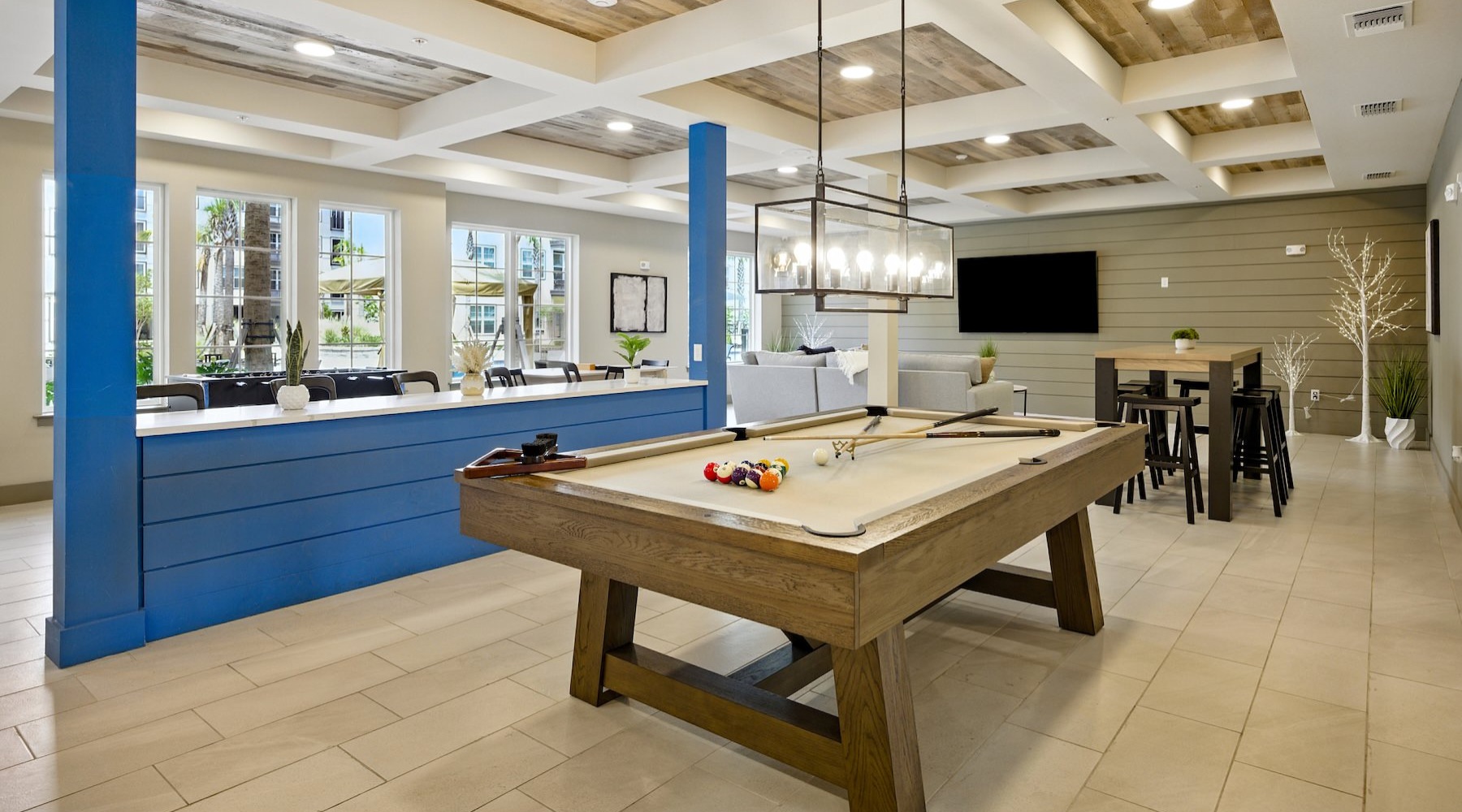 a clubroom with a pool table, tv, table and chairs