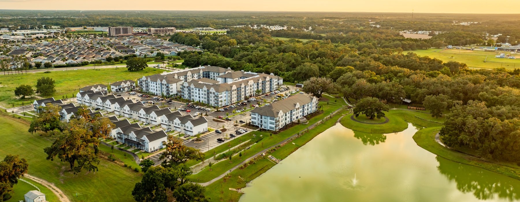 an aerial view of a neighborhood with trees and a lake