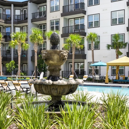 a fountain in a courtyard by a pool and chairs